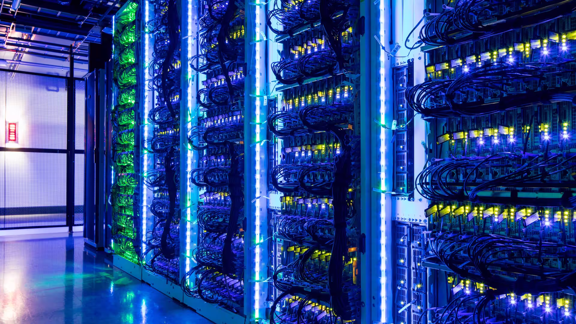 Corredor de racks de datacenter com iluminação azul e luzes de equipamento acesas
